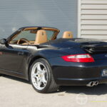 Porsche 911 type 997 Carrera 2 Cabriolet 3.6 325 ch BVM6 — vue trois-quarts arrière décapotée